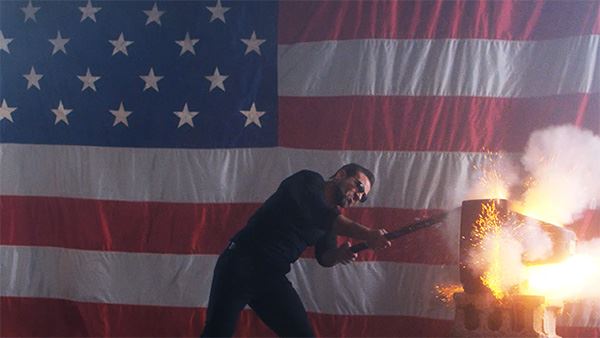 Jamie Casino smashing a TV with a sledgehammer with an American flag backdrop